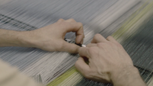 Hands adjusting the threads on the loom