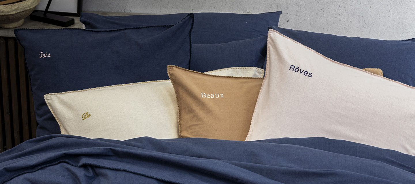 Housses de coussins brodées sur un lit bleu nuit